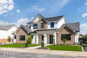 View of front of house featuring a front yard, covered porch, brick siding, and stucco siding