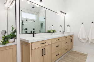 Bathroom with double vanity, a marble finish shower, and light marble finish floors