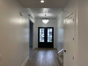 Doorway to outside featuring hardwood / wood-style flooring, a chandelier, and ornamental molding
