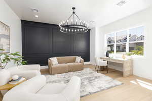 Living area featuring a desk, light wood-style floors, and suspended lighting