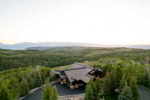 Aerial view of property and surrounding area featuring a heavily wooded area and a mountain backdrop