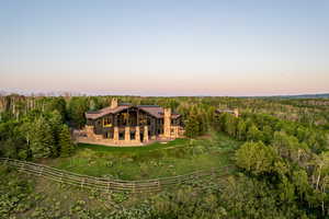 Back of house with a chimney, a wooded view, and stone siding