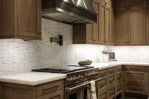 Kitchen with high end range, wall chimney range hood, tasteful backsplash, and light countertops