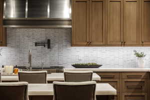 Kitchen with decorative backsplash, light countertops, and brown cabinetry