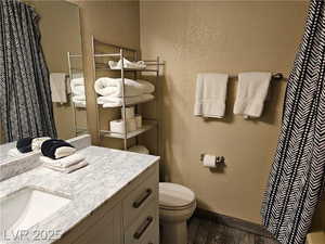 Full bathroom featuring wood finished floors, vanity, a textured wall, and curtained shower
