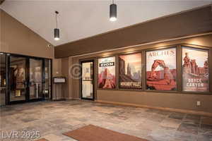Cinema featuring stone finish flooring, high vaulted ceiling, and french doors