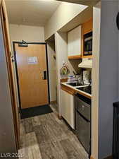 Kitchen with white cabinets, dark wood finished floors, stainless steel microwave, under cabinet range hood, and light countertops
