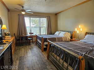 Bedroom featuring crown molding, dark wood-style floors, and a textured ceiling