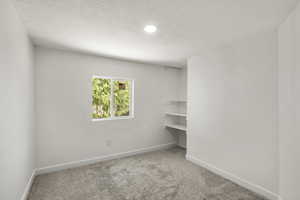 Empty room with carpet flooring, a textured ceiling, and recessed lighting