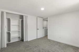 Unfurnished bedroom with washer / dryer, carpet flooring, a closet, recessed lighting, and a textured ceiling