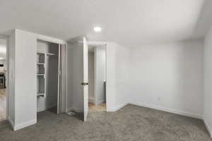 Unfurnished bedroom featuring carpet, a closet, a textured ceiling, and recessed lighting