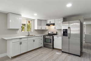 Kitchen featuring appliances with stainless steel finishes, under cabinet range hood, light wood-style floors, light countertops, and recessed lighting