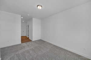Carpeted spare room with baseboards and recessed lighting