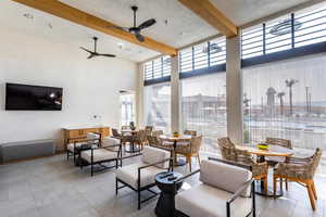 Tiled dining area with a high ceiling, beamed ceiling, and a ceiling fan