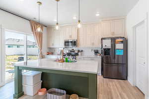 Kitchen featuring stainless steel appliances, light wood-style flooring, light countertops, decorative backsplash, and recessed lighting