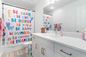Bathroom with vanity, wood finished floors, and shower / bath combo
