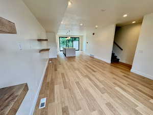 Unfurnished living room with light wood-type flooring, stairs, and recessed lighting