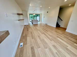 Unfurnished living room with light wood-type flooring, recessed lighting, and stairs