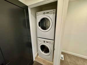 Washroom with stacked washer / drying machine and carpet floors