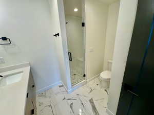 Full bathroom with vanity, a shower stall, marble look tile flooring, and recessed lighting