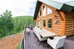 Wooden deck with outdoor dining space, outdoor lounge area, and a view of trees