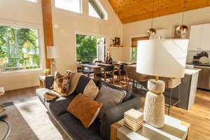 Living area with plenty of natural light, light wood-style floors, high vaulted ceiling, and wood ceiling