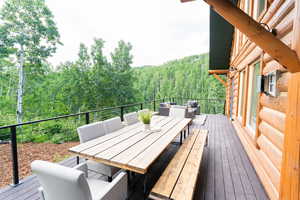 Deck featuring a view of trees, an outdoor hangout area, and outdoor dining area