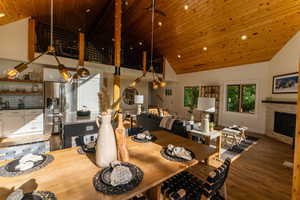 Dining space featuring wood ceiling, high vaulted ceiling, wood finished floors, a fireplace, and recessed lighting