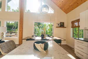 Dining room with high vaulted ceiling, dark wood-style floors, and wooden ceiling
