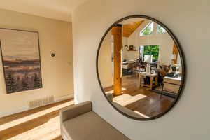 Corridor with wood finished floors and lofted ceiling