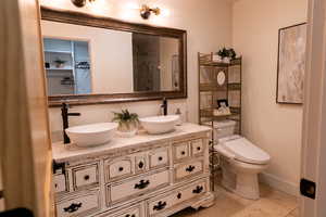 Full bath with double vanity, a shower, and tile patterned flooring