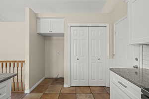 Kitchen with granite counters, white cabinetry, and pantry