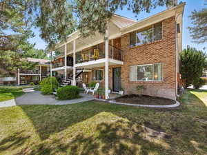 View of front facade with brick siding, a front yard, a balcony, and stairway
