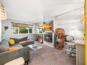Carpeted living area featuring a glass covered fireplace and baseboards