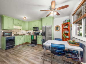 Kitchen featuring black appliances, a ceiling fan, tasteful backsplash, and wood finished floors