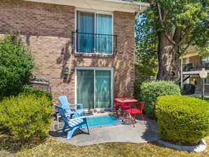Rear view of property with a balcony, brick siding, and a patio area