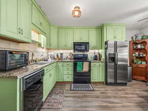 Kitchen with black appliances, light wood-style floors, and backsplash