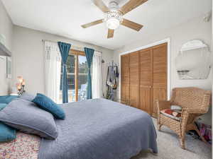 Carpeted bedroom with a closet, ceiling fan, and access to exterior