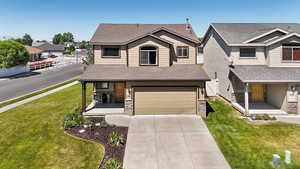 View of front of home with a porch, roof with shingles, driveway, a garage, and stone siding
