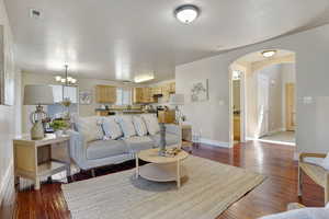 Living room featuring arched walkways, wood-type flooring, and a chandelier