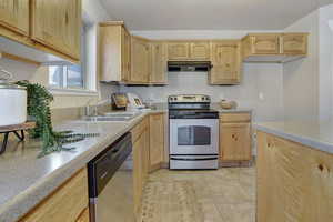 Kitchen with appliances with stainless steel finishes, under cabinet range hood, and light brown cabinets