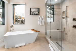 Bathroom with a freestanding tub, a shower stall, healthy amount of natural light, and tile patterned flooring