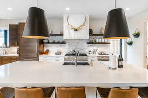 Kitchen with modern cabinets, open shelves, light countertops, backsplash, and a breakfast bar area