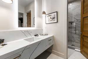 Bathroom featuring a marble finish shower, vanity, tile patterned floors, and tasteful backsplash