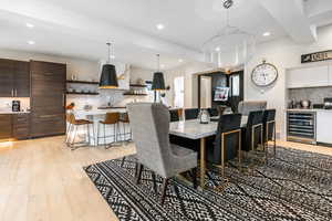 Dining space with wine cooler, recessed lighting, light wood-style floors, and bar
