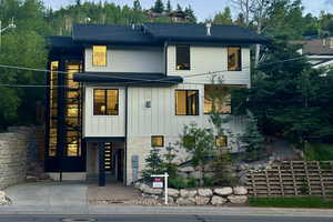 Contemporary home featuring board and batten siding, stone siding, and stairway