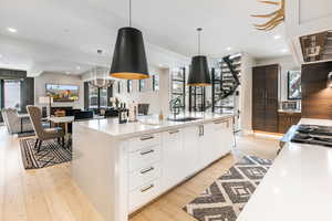 Kitchen featuring modern cabinets, white cabinets, light wood-style floors, hanging light fixtures, and light countertops