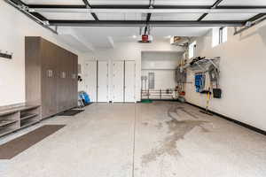 Garage featuring a garage door opener, electric panel, and a wall mounted AC