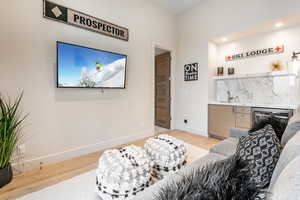 Living area with light wood-type flooring, beverage cooler, recessed lighting, and bar