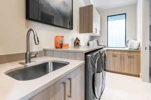 Laundry room featuring cabinet space, washer and dryer, and light tile patterned floors